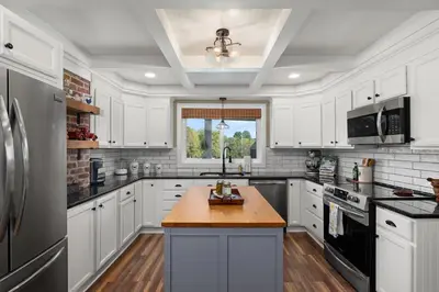a kitchen with white cabinets and a wooden counter top at Historic Farmhouse with Pool & Barn in Mansfield