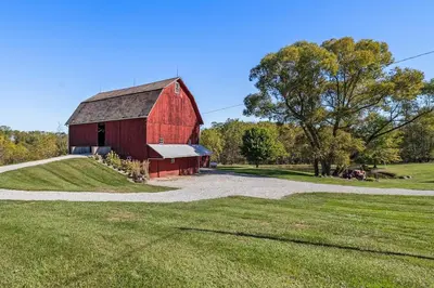 a red barn on a field with a road at Historic Farmhouse with Pool & Barn in Mansfield