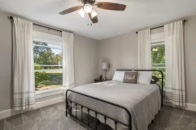 a bedroom with a bed with a ceiling fan and windows at Historic Farmhouse with Pool & Barn in Mansfield