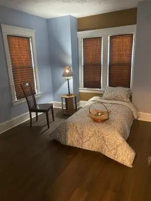 a bedroom with a bed and a chair and windows at 1469 east 116th in Cleveland