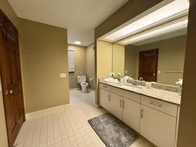 a bathroom with two sinks and a toilet and a mirror at Luxury 5BR Estate: Media Room & Golf | Sleeps 14 in Sylvania