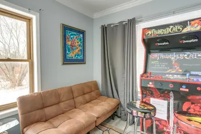 a living room with a couch and a pinball machine at 7 Mi to Cedar Point Retreat with Hot Tub and Gazebo in Huron