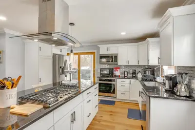 a kitchen with white cabinets and stainless steel appliances at 7 Mi to Cedar Point Retreat with Hot Tub and Gazebo in Huron