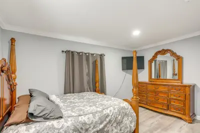 a bedroom with a bed and a dresser and a mirror at 7 Mi to Cedar Point Retreat with Hot Tub and Gazebo in Huron