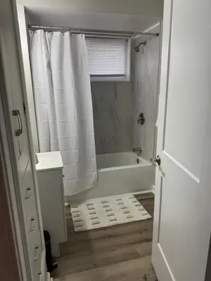 a white bathroom with a tub and a shower at The Cozy Cottonwood Cottage- Clintonville 3BRM Ranch in Columbus