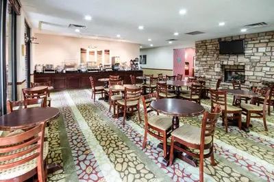 a restaurant with tables and chairs and a fireplace at River Bluff Hotel and Conference Center in Mineralwells