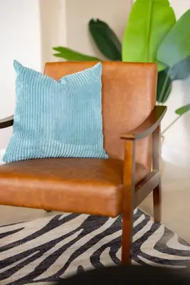 a brown chair with a blue pillow on a rug at Downtown 2BR | Walk to Venues, Play house Square in Cleveland