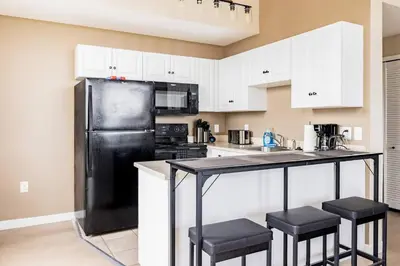 a kitchen with a black refrigerator and black stools at Downtown 2BR | Walk to Venues, Play house Square in Cleveland