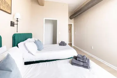 a bedroom with two beds and a green chair at Downtown 2BR | Walk to Venues, Play house Square in Cleveland