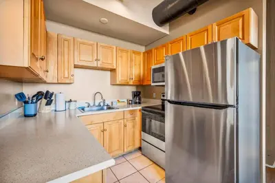 a kitchen with a stainless steel refrigerator and wooden cabinets at Fun 2Bed Apt Skeeball Foosball FREE Parking in Cleveland