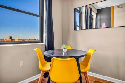 a dining room table with yellow chairs and a mirror at Colorful 2Bed Apt Heart of Downtown Lake Views in Cleveland