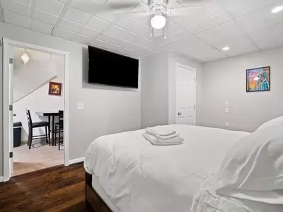 a white bedroom with a bed and a flat screen tv at Fun 3 BR Home in Ohio City Game Room Sleeps 11 in Cleveland