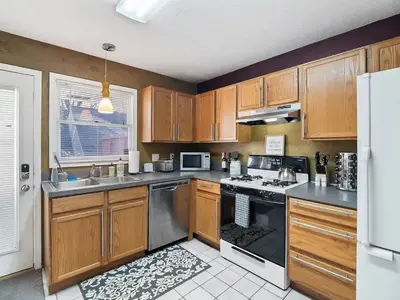 a kitchen with wooden cabinets and a stove top oven at Fun 3 BR Home in Ohio City Game Room Sleeps 11 in Cleveland
