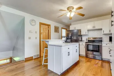 a kitchen with white cabinets and a ceiling fan at Shady Point Retreat with Hot Tub and Pickleball! in Killbuck