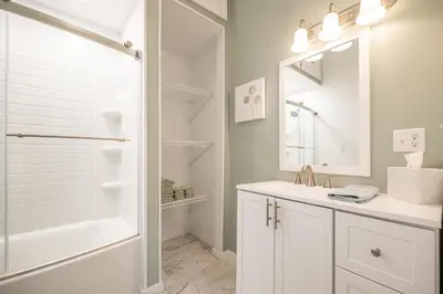 a white bathroom with a sink and a shower at Shady Point Retreat with Hot Tub and Pickleball! in Killbuck