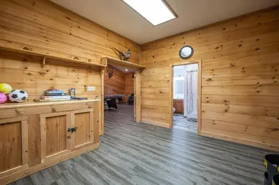 a room with wooden walls and a clock on the wall at Shady Point Retreat with Hot Tub and Pickleball! in Killbuck