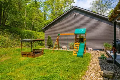 a playground with a slide and a swing set at Shady Point Retreat with Hot Tub and Pickleball! in Killbuck