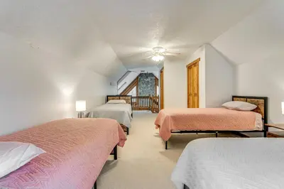 a bedroom with three beds and a staircase at Shady Point Retreat with Hot Tub and Pickleball! in Killbuck
