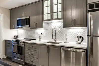 a kitchen with stainless steel appliances and gray cabinets at Walk to OTR! Hot Tub and Movie Room at Cincy Condo in Cincinnati