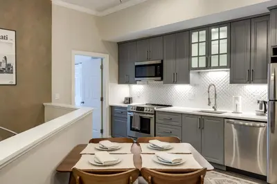 a kitchen with a wooden table and a sink at Walk to OTR! Hot Tub and Movie Room at Cincy Condo in Cincinnati