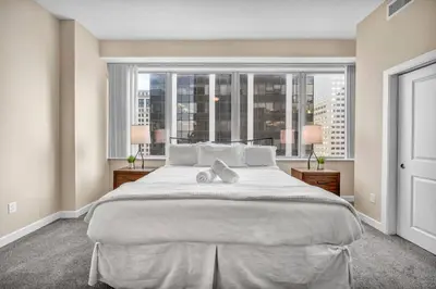 a large bed in a bedroom with a large window at LAKE VIEW Sky-Suite in the Heart of Downtown! in Cleveland