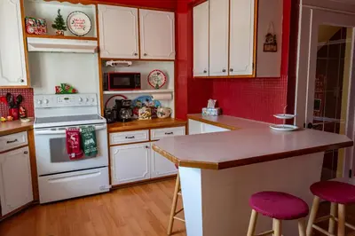 a kitchen with white appliances and red walls at 4BR- Downtown Christmas Home in Millersburg