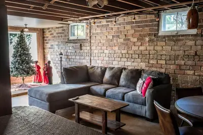 a living room with a couch and a brick wall at 4BR- Downtown Christmas Home in Millersburg
