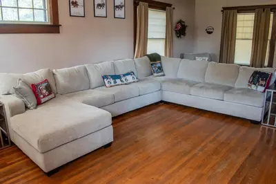 a living room with a large couch and wooden floors at 4BR- Downtown Christmas Home in Millersburg