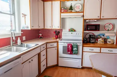 a kitchen with white cabinets and a white stove top oven at 4BR- Downtown Christmas Home in Millersburg