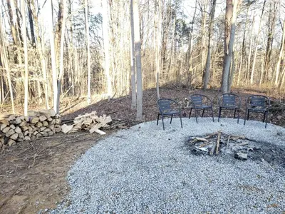 two chairs sitting next to a fire in the woods at King of Hearts in Rockbridge