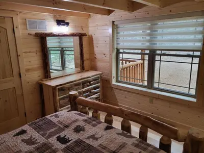 a bedroom of a log cabin with a bed and a window at Jack of Hearts in Rockbridge