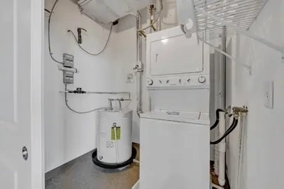 a small white laundry room with a washer and dryer at LAKE VIEWS! 15th Floor Downtown High-Rise | Gym in Cleveland