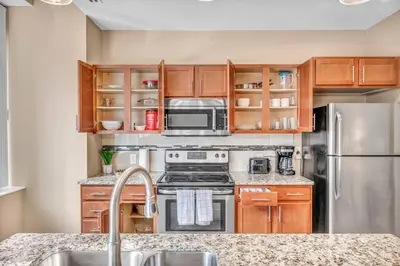 a kitchen with stainless steel appliances and wooden cabinets at Modern High-Rise Condo in Central Downtown | Gym in Cleveland