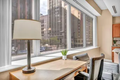 a desk with a lamp and chairs in front of a window at Modern High-Rise Condo in Central Downtown | Gym in Cleveland