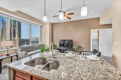 a kitchen with a sink and a living room at Luxury High-Rise Condo in Amazing Location | Gym in Cleveland