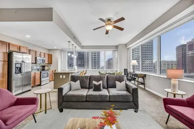 a living room with a couch and a kitchen at 10th Floor Downtown High-Rise | Gym in Cleveland