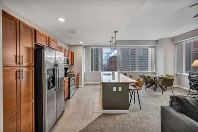 a kitchen with stainless steel appliances and a living room at 10th Floor Downtown High-Rise | Gym in Cleveland