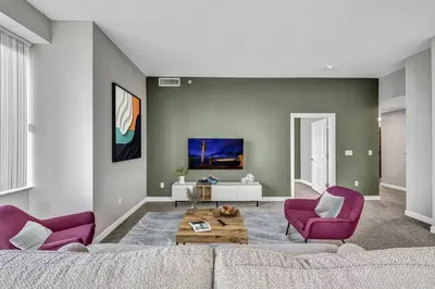 a living room with a couch and two purple chairs at 14th Floor Lux Downtown Condo w/ LAKE VIEWS & Gym in Cleveland