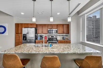 a kitchen with a sink and a counter with chairs at 14th Floor Lux Downtown Condo w/ LAKE VIEWS & Gym in Cleveland