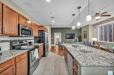 a kitchen with stainless steel appliances and a living room at 16th Floor Downtown High-Rise | Paid Parking & Gym in Cleveland