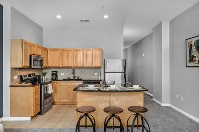 a kitchen with wooden cabinets and bar stools at Epic Downtown Pad • Entertain & Unwind in Cleveland
