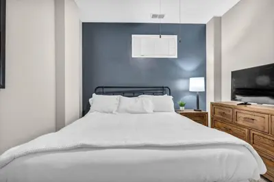 a bedroom with a white bed with a blue wall at Epic Downtown Pad • Entertain & Unwind in Cleveland