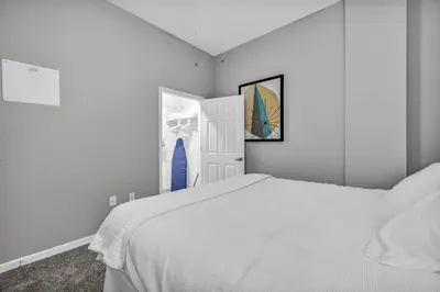 a white bedroom with a white bed and an open door at Epic Downtown Pad • Entertain & Unwind in Cleveland