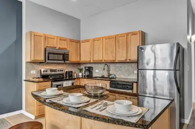 a kitchen with wooden cabinets and a stainless steel refrigerator at Epic Downtown Pad • Entertain & Unwind in Cleveland
