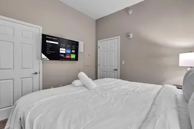 a bedroom with a white bed with a tv on the wall at The Playhouse Suites 1BD | Parking | Downtown in Cleveland