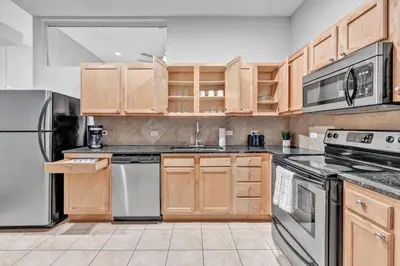 a kitchen with wooden cabinets and stainless steel appliances at Comfy City Vibe • Theater District Gem in Cleveland