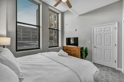 a white bedroom with a bed and a tv at Large 1BD FLAT in the Heart of Downtown in Cleveland