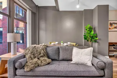 a living room with a gray couch with a blanket at Comfy City Vibe • Walk to Theaters + Parking $ in Cleveland