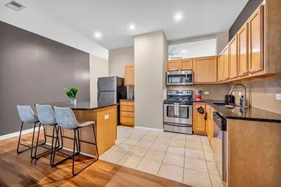 a kitchen with wooden cabinets and bar stools at Play & Stay Loft Central, Comfy, Parking in Cleveland