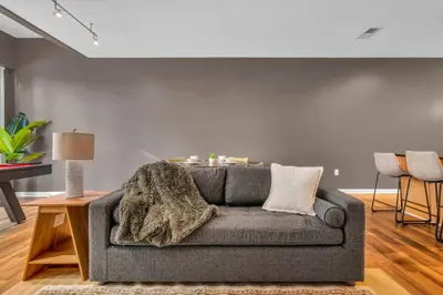 a living room with a gray couch and a table at Play & Stay Loft Central, Comfy, Parking in Cleveland